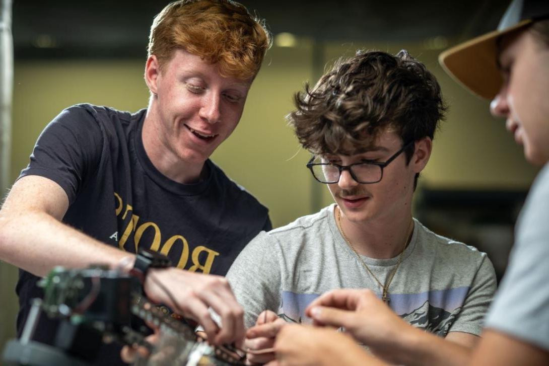 Three students using equipment